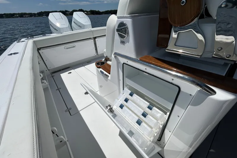 Slide: The Image of 2027 Everglades 315 Center Console boat interior with open storage compartment and twin Mercury engines. - 33