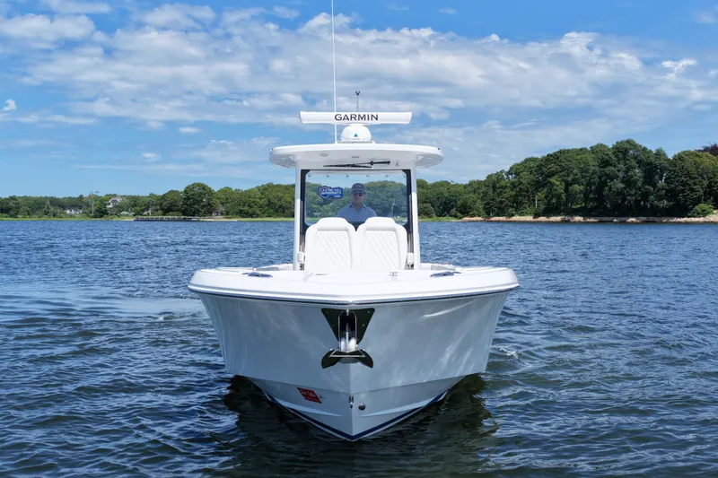 Slide: The Image of 2027 Everglades 315 Center Console boat on water, clear sky, lush shoreline in background. - 1
