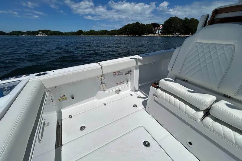 Slide: The Image of 2027 Everglades 315 Center Console boat interior with white seating, on a scenic lake. - 31
