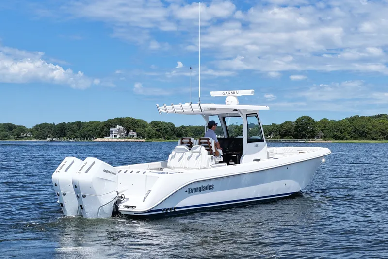 Slide: The Image of 2027 Everglades 315 Center Console boat cruising on a scenic lake under a blue sky. - 5