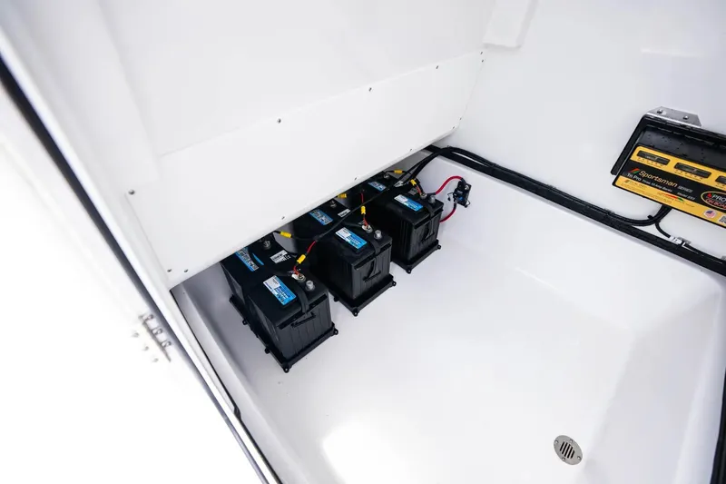 Slide: The Image of 2026 Sportsman Masters 267 Bay Boat battery compartment with multiple batteries and charger. - 13