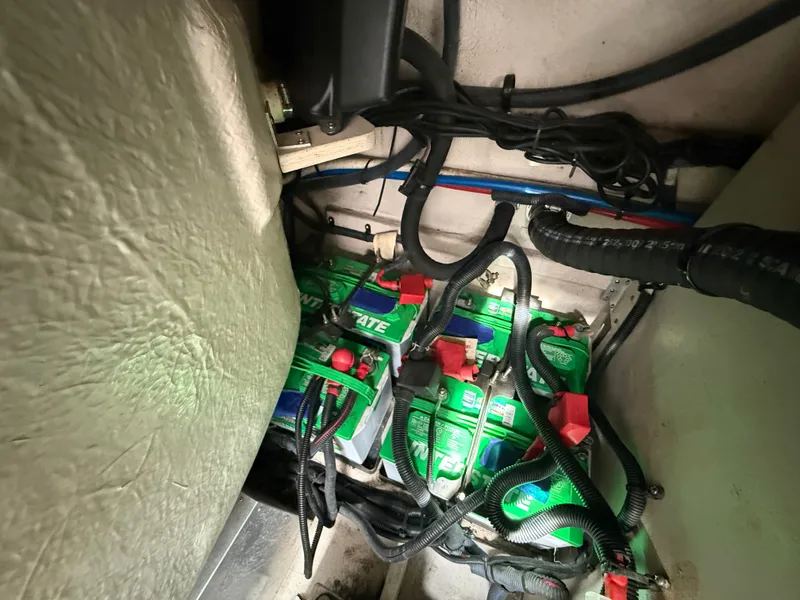 Slide: The Image of Batteries and wiring in a boat's engine compartment, surrounded by cables and hoses. - 47