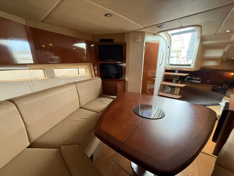 Slide: The Image of Interior of a 2013 Sea Ray 370 Venture with beige sofa, wooden table, and stairs to cabin. - 32