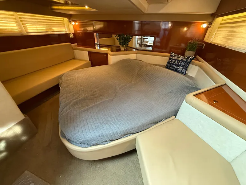 Slide: The Image of The 2013 Sea Ray 370 Venture cabin features a large bed, seating, and wood accents. - 39