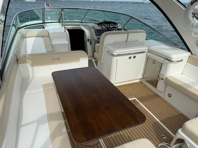 Slide: The Image of The image shows the cockpit of a 2013 Sea Ray 370 Venture with a wooden table and beige seating. - 10
