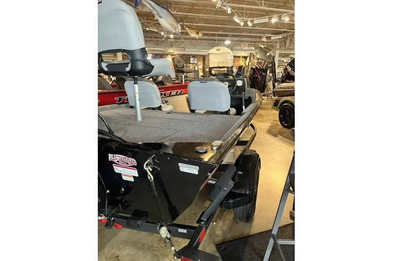 Slide: The Image of 2027 Tracker Bass Tracker Classic XL boat displayed in showroom, featuring seating and carpeted deck. - 11