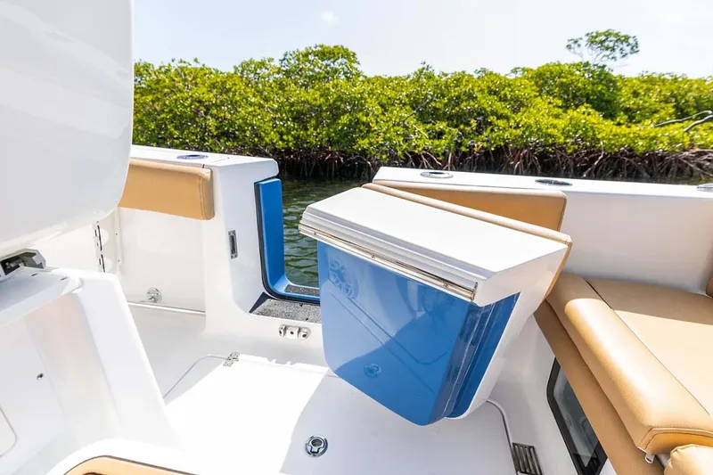 Slide: The Image of Manufacturer Provided Image: 2025 Sportsman Heritage 261 Center Console interior with seating and storage, near lush greenery. - 7