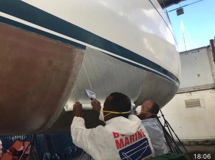 Slide: The Image of Two people work on the hull of a 1979 Nautor Swan 441 in a boatyard. - 25