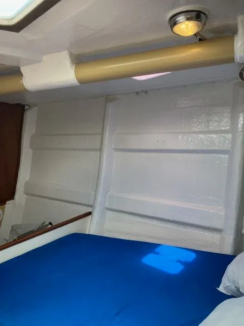 Slide: The Image of Interior of a 1979 Nautor Swan 441 with a blue bed and white painted walls. - 15