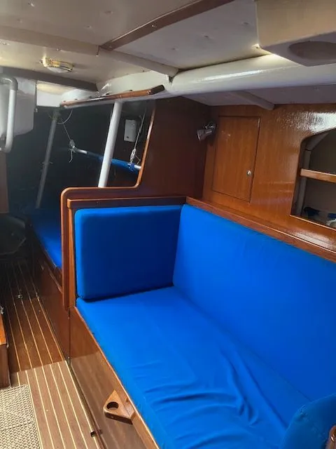 Slide: The Image of Interior of a 1979 Nautor Swan 441 with blue cushions and wooden fittings. - 12