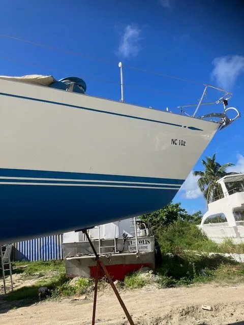 Slide: The Image of The 1979 Nautor Swan 441 is on a stand, surrounded by other boats and palm trees. - 6
