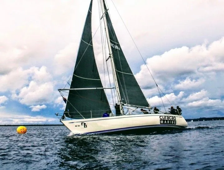 The Image of A 1979 Nautor Swan 441 sailing on open water with black sails and a yellow buoy. - 0