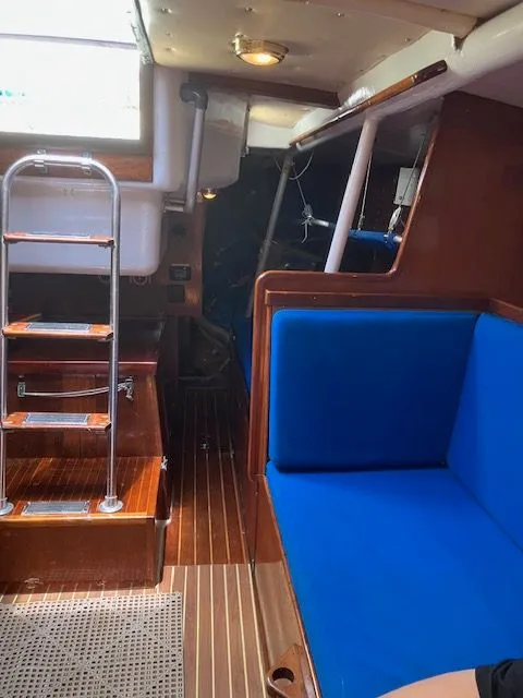 Slide: The Image of Interior of a 1979 Nautor Swan 441 with blue upholstery and wooden flooring. - 17