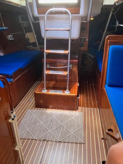 Slide: The Image of Interior of a 1979 Nautor Swan 441 with wooden flooring and blue cushions. - 16
