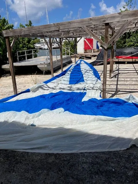 Slide: The Image of A blue and white sail is spread out on a frame near a waterway. - 21