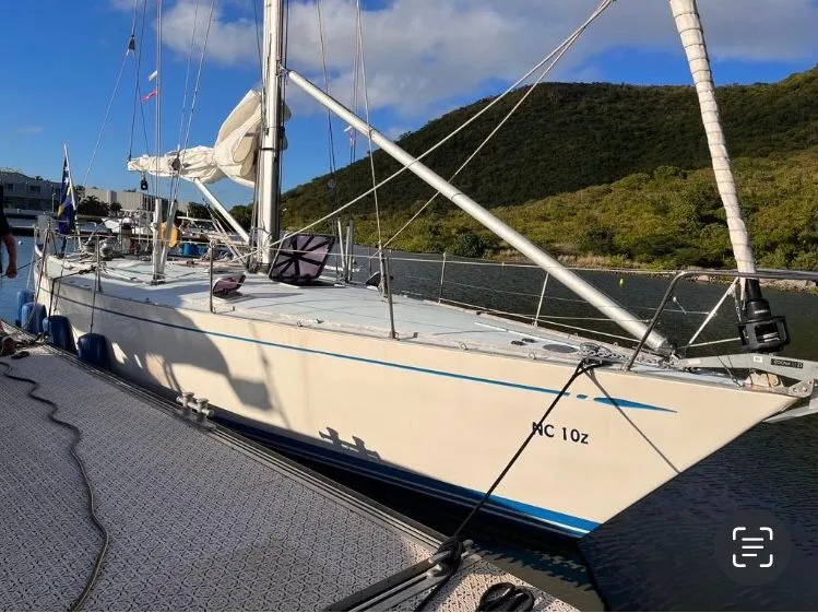 Slide: The Image of A 1979 Nautor Swan 441 docked beside a wooded hillside, with sails neatly stowed. - 3