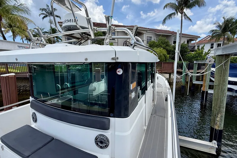 Slide: The Image of 2018 Axopar 37 Sports Cabin docked near palm trees and waterfront homes. - 25