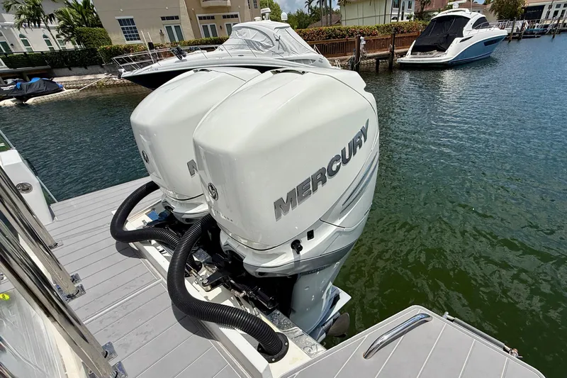 Slide: The Image of Twin Mercury outboard engines on a 2018 Axopar 37 Sports Cabin, docked by waterfront homes. - 13