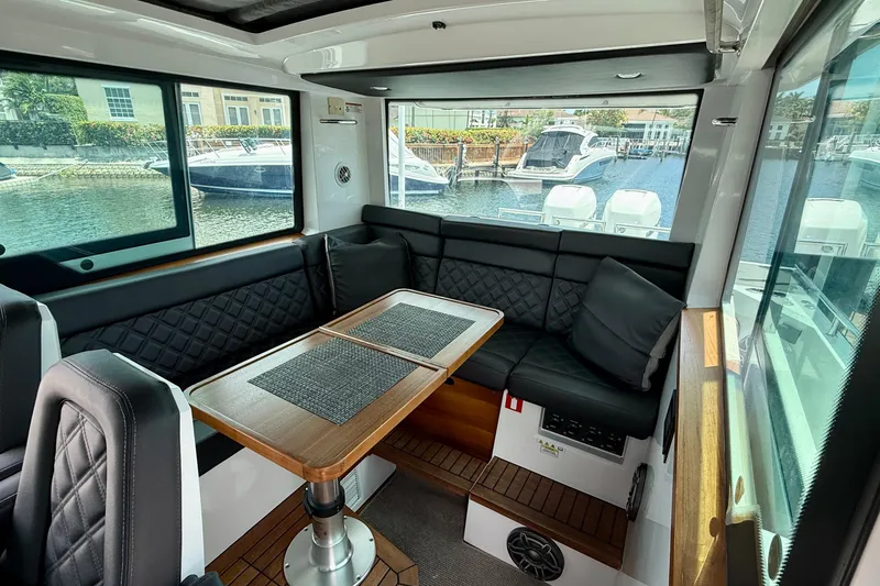 Slide: The Image of Interior of 2018 Axopar 37 Sports Cabin with seating and table, docked by water. - 43