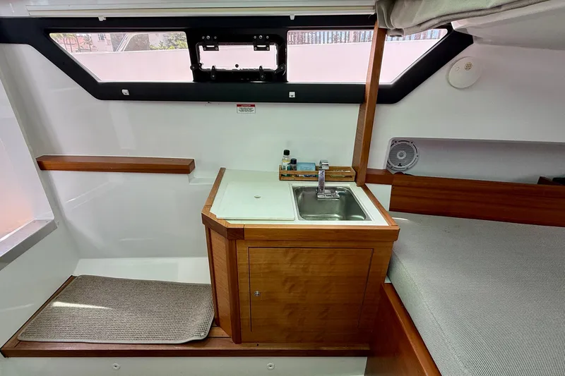 Slide: The Image of 2018 Axopar 37 Sports Cabin interior with sink, wooden cabinetry, and window view. - 47