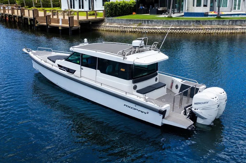 Slide: The Image of 2018 Axopar 37 Sports Cabin boat on calm water, featuring sleek design and twin Mercury engines. - 3