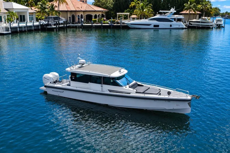 Slide: The Image of 2018 Axopar 37 Sports Cabin boat on calm blue water near luxury waterfront homes. - 9