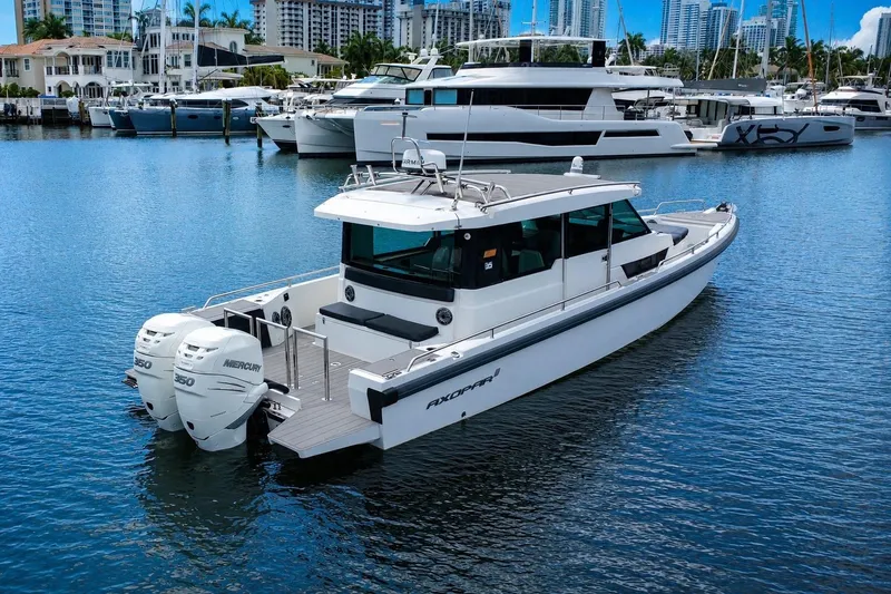 Slide: The Image of 2018 Axopar 37 Sports Cabin boat docked in a marina with luxury yachts. - 7
