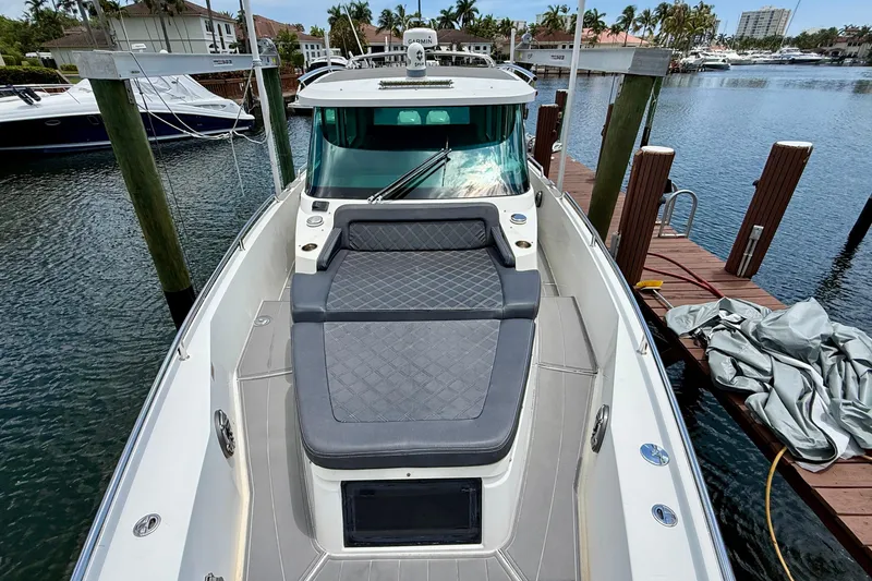 Slide: The Image of 2018 Axopar 37 Sports Cabin boat docked at marina, featuring cushioned seating area. - 30