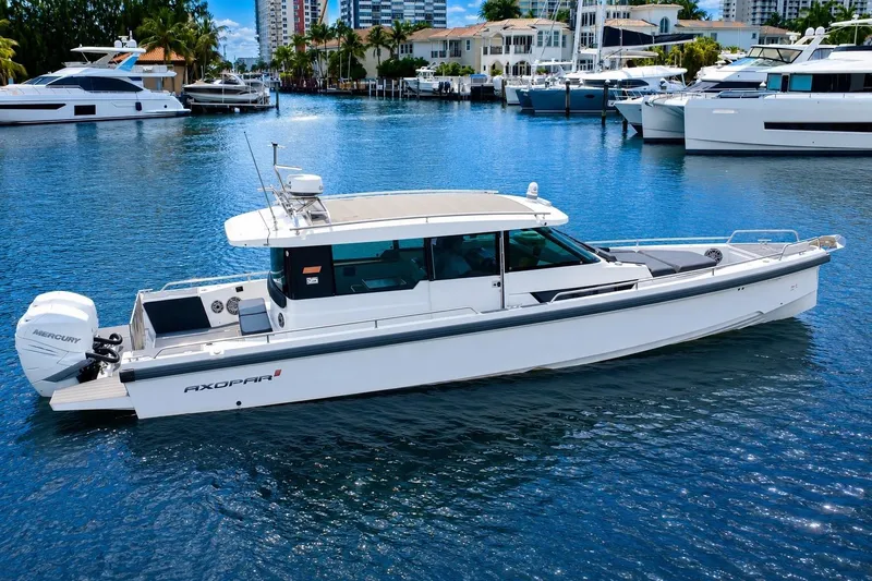 Slide: The Image of 2018 Axopar 37 Sports Cabin boat on a serene marina with luxury yachts. - 8