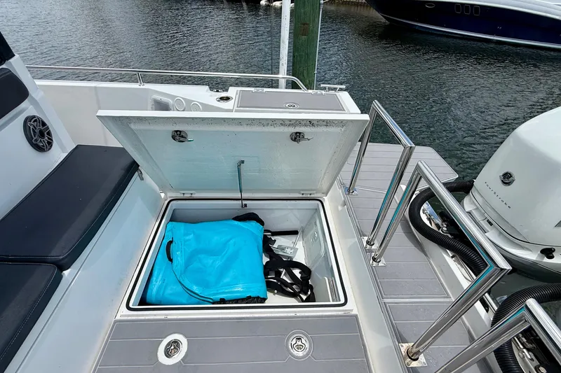 Slide: The Image of 2018 Axopar 37 Sports Cabin storage compartment with blue bag, docked by water. - 21