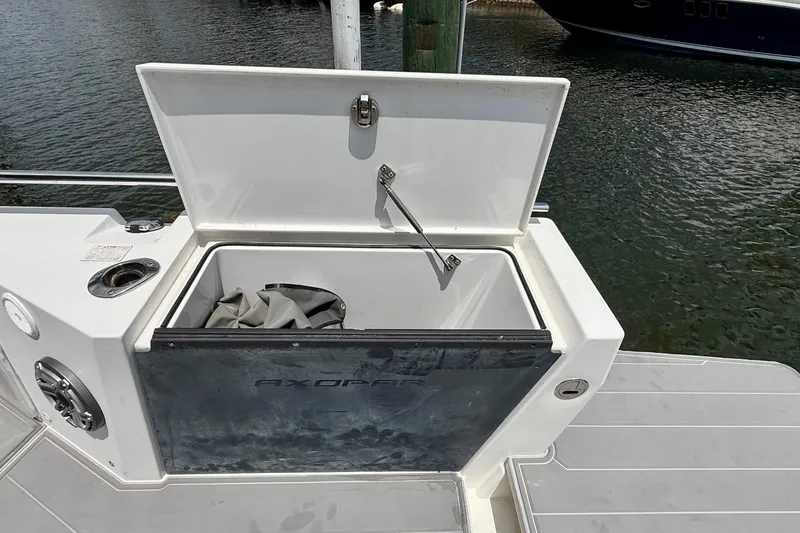 Slide: The Image of Open storage compartment on 2018 Axopar 37 Sports Cabin boat by the water. - 17