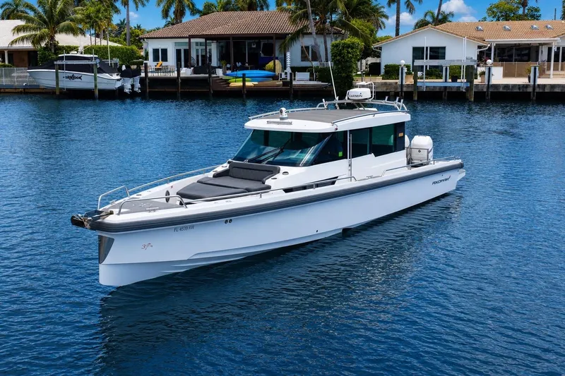 Slide: The Image of 2018 Axopar 37 Sports Cabin boat on calm water near waterfront homes. - 2