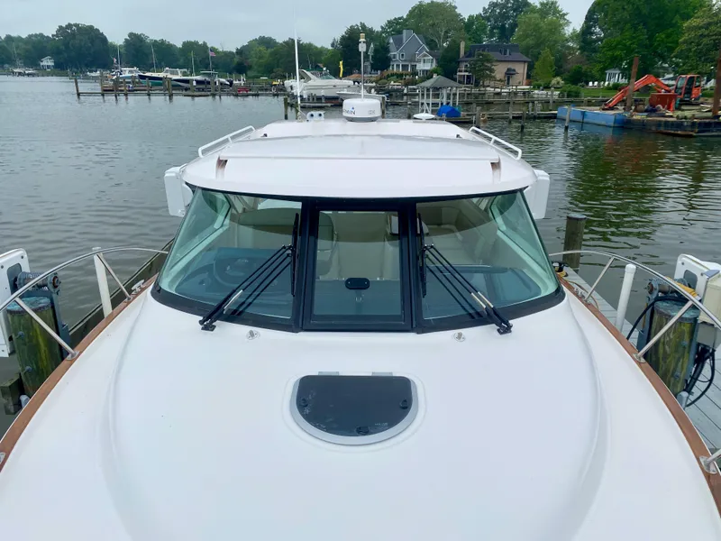 Slide: The Image of The 2012 Tiara Yachts 3100 Coronet is docked at a serene harbor with surrounding houses. - 18