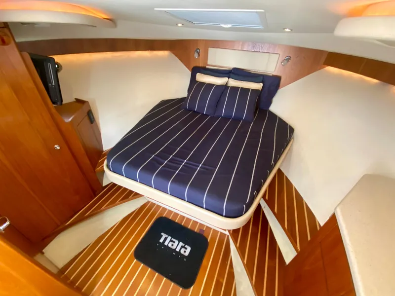 Slide: The Image of The 2012 Tiara Yachts 3100 Coronet cabin features a cozy bed with striped bedding. - 21