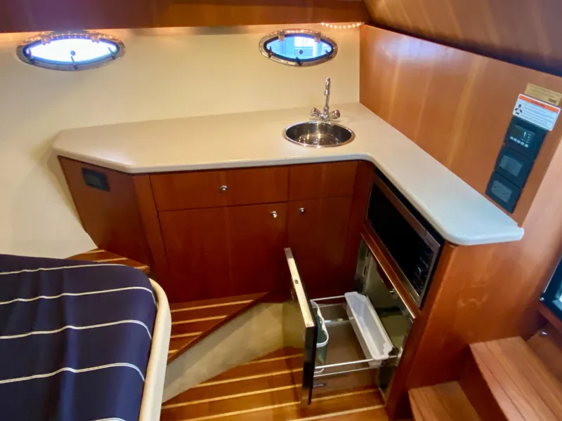 Slide: The Image of Interior of the 2012 Tiara Yachts 3100 Coronet featuring a small kitchenette, sink, and drawers. - 23