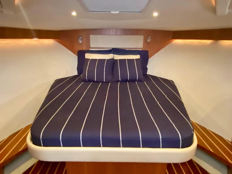 Slide: The Image of The cabin of the 2012 Tiara Yachts 3100 Coronet features a cozy bed with striped bedding. - 26