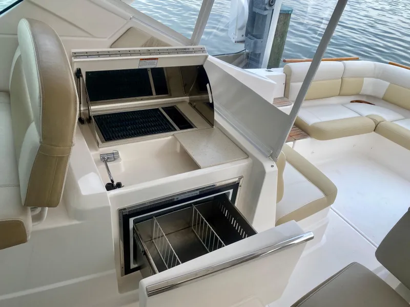 Slide: The Image of The image shows the interior of a 2012 Tiara Yachts 3100 Coronet with an open cooler and beige seating. - 14