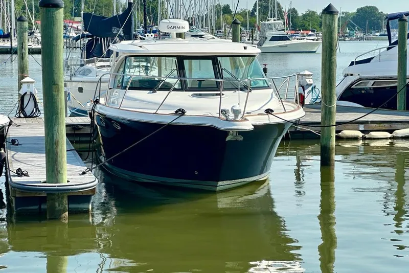 Slide: The Image of 2012 Tiara Yachts 3100 Coronet docked at a marina, surrounded by boats. - 2