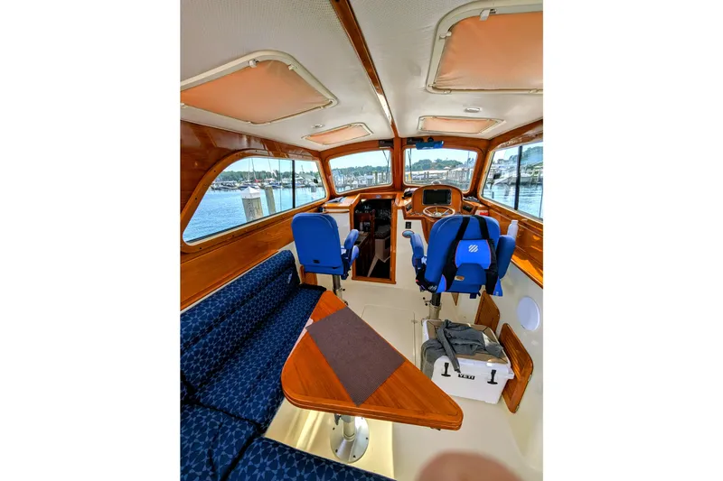 Slide: The Image of Interior of 2003 Hinckley Picnic Boat 36 EP with blue seating and wooden accents. - 21
