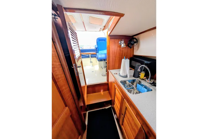 Slide: The Image of Interior of 2003 Hinckley Picnic Boat 36 EP, featuring a compact galley with wooden cabinetry. - 33