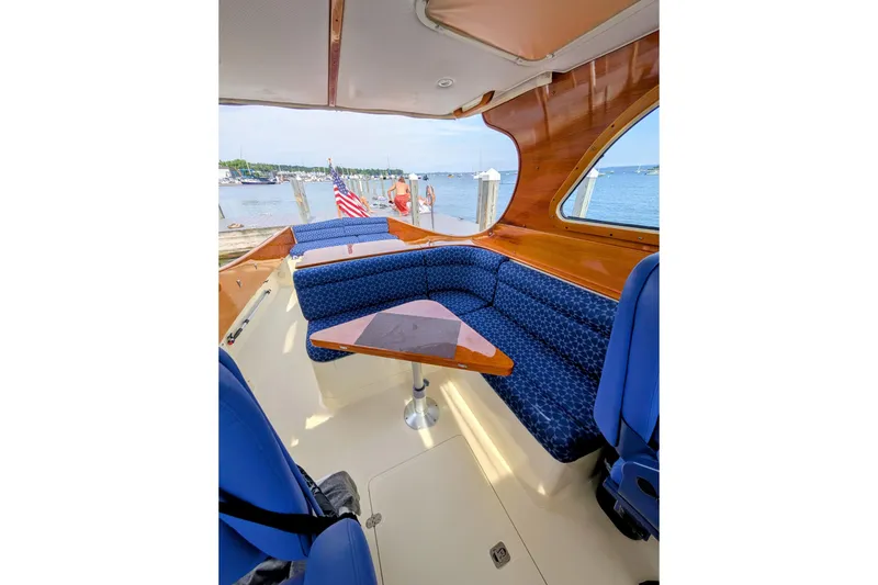 Slide: The Image of 2003 Hinckley Picnic Boat 36 EP interior with blue seating and wooden accents by the water. - 20