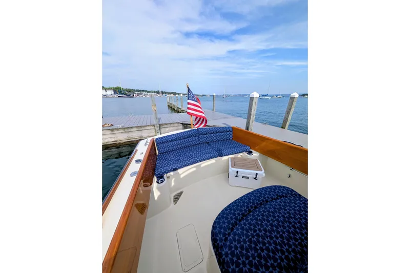 Slide: The Image of 2003 Hinckley Picnic Boat 36 EP docked with American flag, blue seating, and scenic harbor view. - 19