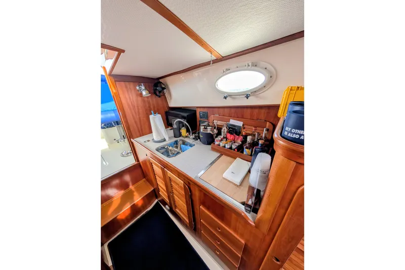 Slide: The Image of Interior of 2003 Hinckley Picnic Boat 36 EP galley with wooden cabinetry and countertop. - 34