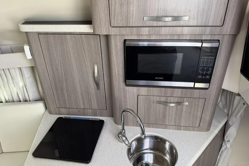 Slide: The Image of Compact kitchen area in a 2019 Regal 28 Express boat with microwave and sink. - 15