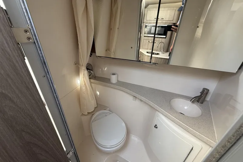 Slide: The Image of Bathroom interior of 2019 Regal 28 Express boat, featuring sink, toilet, and mirror. - 16