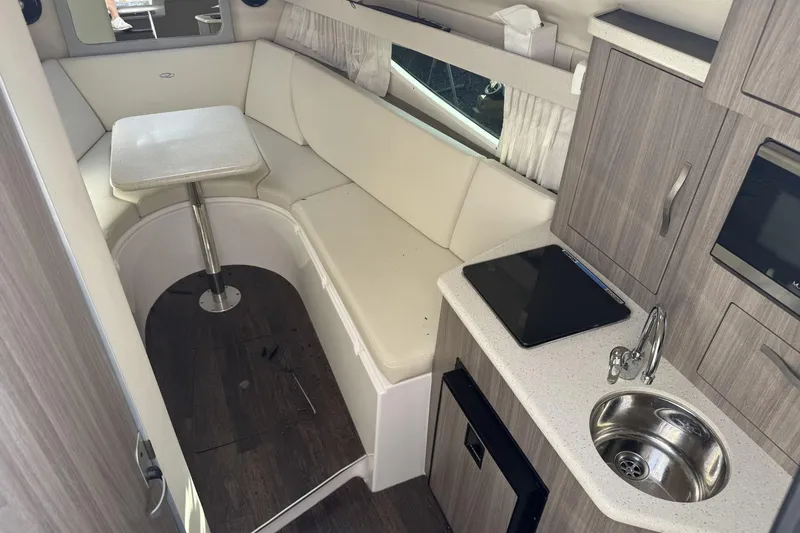 Slide: The Image of 2019 Regal 28 Express cabin interior with seating, table, kitchenette, and modern amenities. - 13