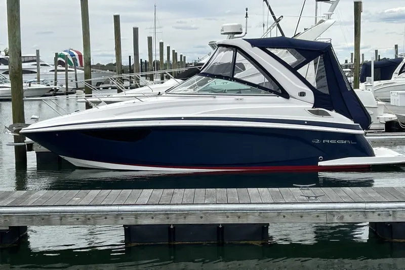 The Image of 2019 Regal 28 Express boat docked at marina, featuring sleek design and blue hull. - 1