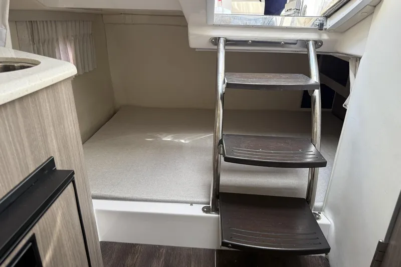Slide: The Image of Interior of 2019 Regal 28 Express boat with ladder and sleeping area. - 14