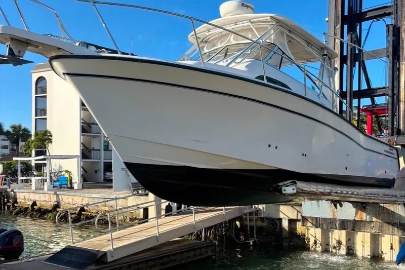 Slide: The Image of 2004 Grady-White Marlin 300 boat lifted at marina, clear sky background. - 1
