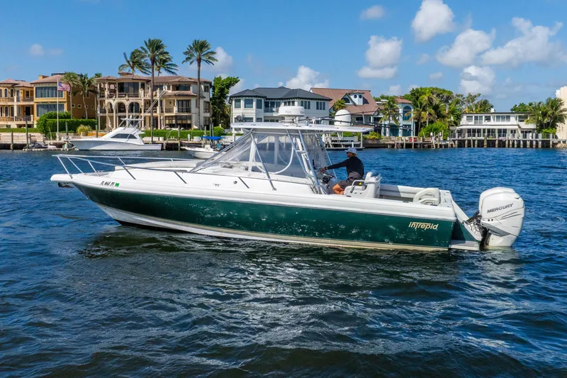 Slide: The Image of 2003 Intrepid 348 Walkaround boat cruising on a sunny day near waterfront homes. - 11